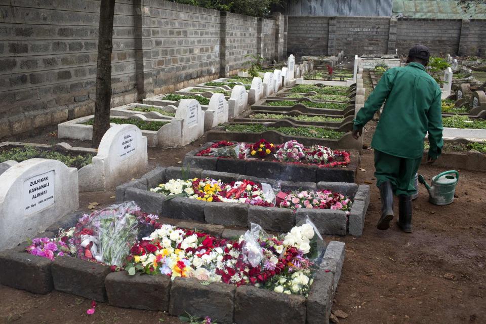 A cemetery worker walks near the fresh graves of Selima Merali and her daughter Nuriana Merali, who were killed in the attack by gunmen at the Westgate Shopping Centre in Nairobi