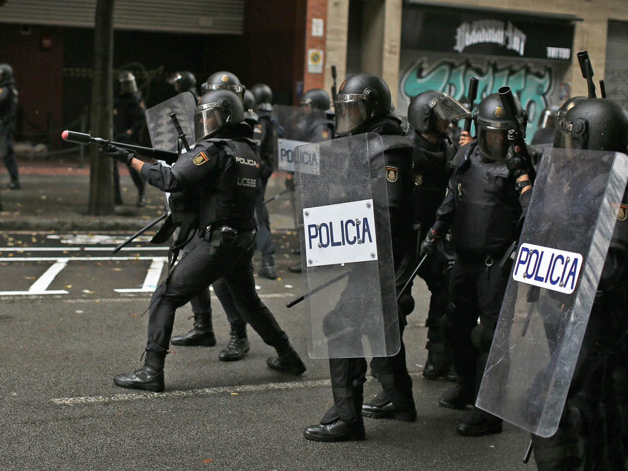 A Spanish National Police officer aims a rubber-bullet rifle at pro-referendum supporters in Barcelona: AP