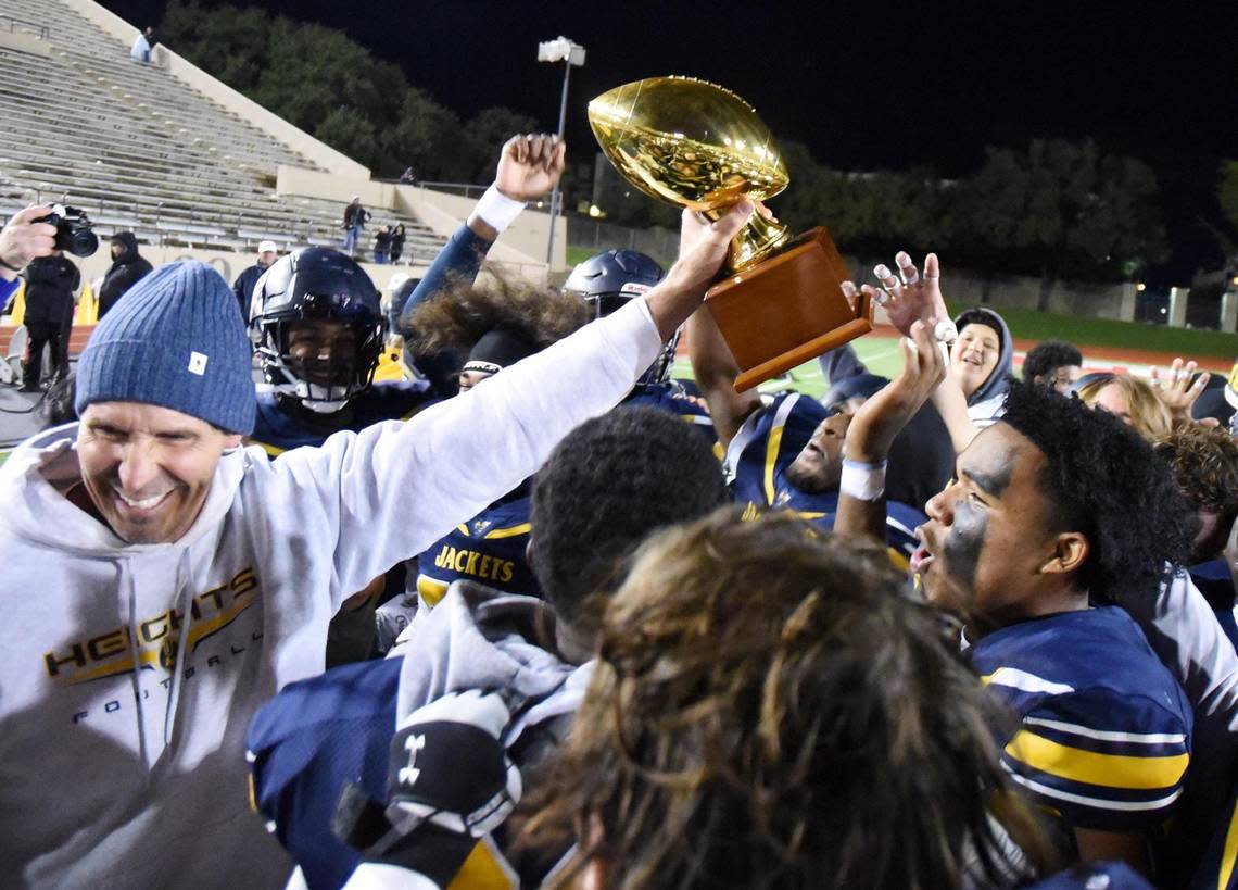 Arlington Heights Head Coach Phil Young, left holds out the he trophy as team members celebrate after beating Frisco Independence High School 40-21 in Friday’s November 11, 2022 5A Division 2 Bi-District football game at Farrington Field in Fort Worth, Texas. Special/Bob Haynes