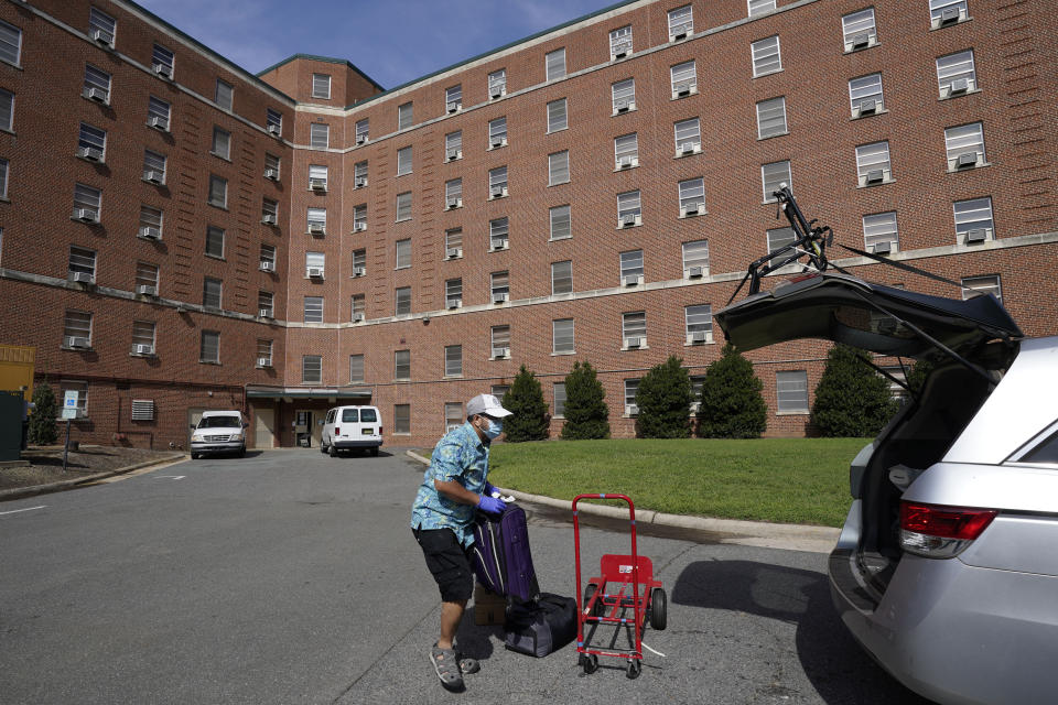 A parent packs a student's belongings at Ehringhaus dormitory following a cluster of COVID-19 cases on campus at the University of North Carolina in Chapel Hill, N.C., Tuesday, Aug. 18, 2020. The university announced that it would cancel all in-person undergraduate learning starting on Wednesday causing some students to pack and leave. (AP Photo/Gerry Broome)