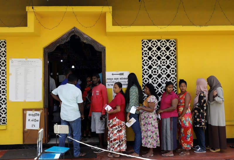 People stand in a line to cast their vote during the presidential election in Colombo