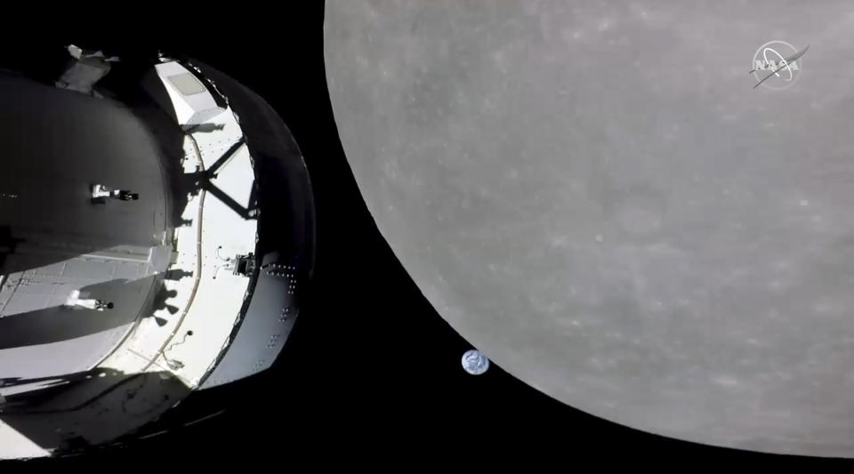 This screengrab from NASA TV shows NASA's Orion capsule, left, nearing the moon, right, Monday, Nov. 21, 2022. At center is earth. (NASA via AP)