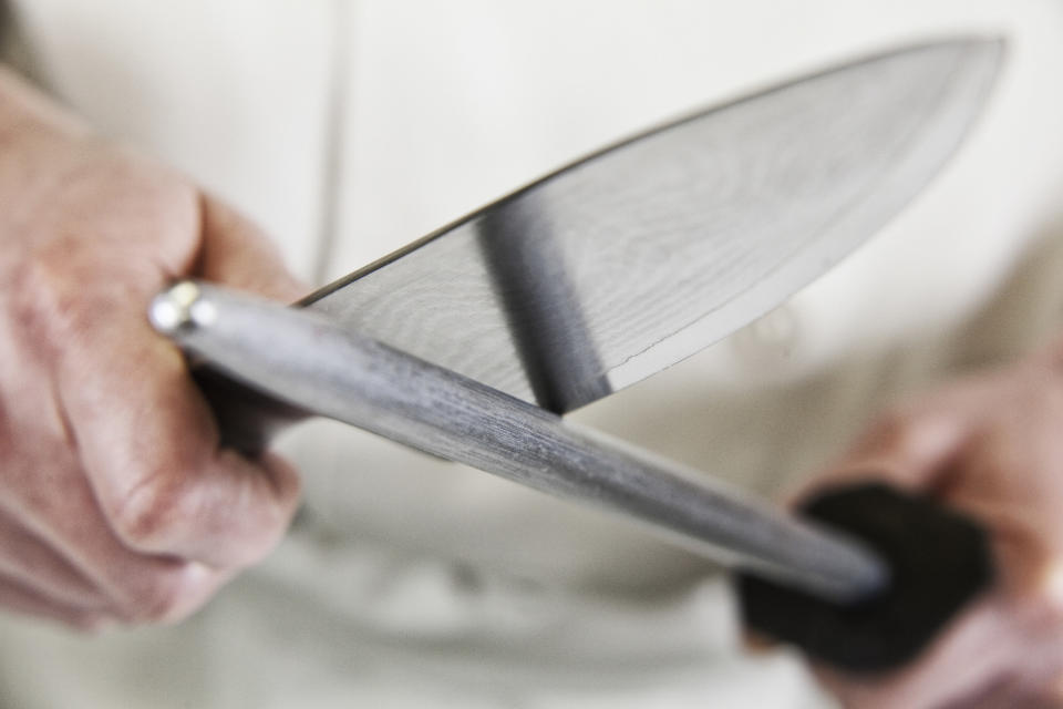 A chef sharpens a large knife