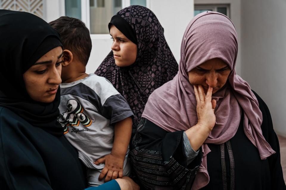 Three women in hijab, one holding a child