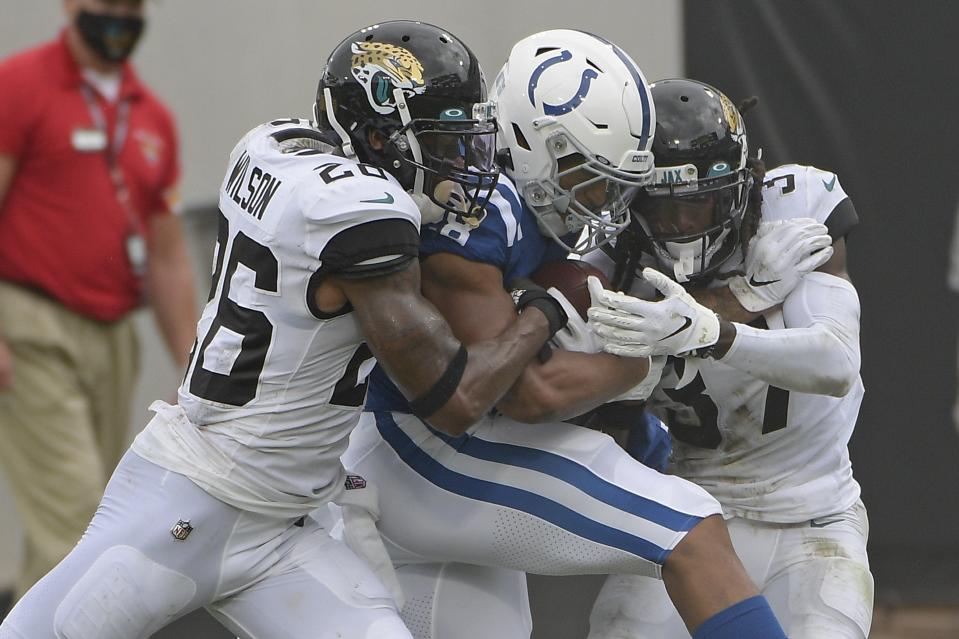 Indianapolis Colts running back Jonathan Taylor, center, is stopped by Jacksonville Jaguars safety Jarrod Wilson, left, and cornerback Tre Herndon, right, after a gain during the first half of an NFL football game, Sunday, Sept. 13, 2020, in Jacksonville, Fla. (AP Photo/Phelan M. Ebenhack)