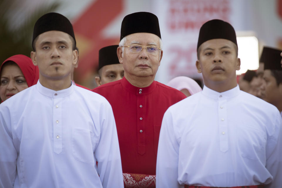 FILE - United Malay's National Organisation (UMNO) party President and Malaysian Prime Minister Najib Razak, center, inspects a ceremonial guard of honor during the opening ceremony of UMNO party's general assembly in Kuala Lumpur, Malaysia, Dec. 7, 2017. Najib Razak on Tuesday, Aug. 23, 2022 was Malaysia’s first former prime minister to go to prison -- a mighty fall for a veteran British-educated politician whose father and uncle were the country’s second and third prime ministers, respectively. The 1MDB financial scandal that brought him down was not just a personal blow but shook the stranglehold his United Malays National Organization party had over Malaysian politics. (AP Photo/Vincent Thian, file)