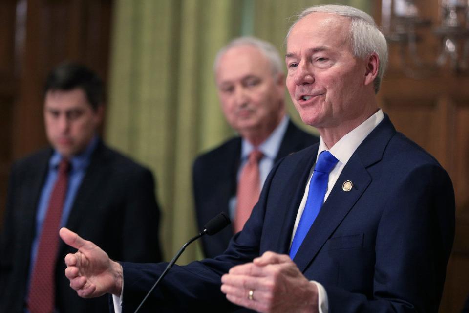 In this March 23, 2020 file photo, Gov. Asa Hutchinson, right, speaks in Little Rock, Ark.