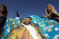 Women carry a fabric with a representation of T.B. Joshua, a Nigerian evangelical preacher, as they attend his religious retreat on Mount Precipice, Nazareth