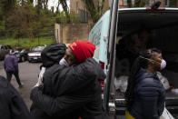 In this March 25, 2020, photo, Angela Stevenson Holmes, left, hugs volunteer Jimmie Jenkins, 30, as he delivers donated groceries to her neighborhood in southeast Washington. At right is volunteer India Blocker-Ford. Neighborhood deliveries are part of a new Martha's Table initiative, along with community partners, to get needed food directly to the neighbors they serve. Local volunteers are the tip of the spear for a grassroots community effort to keep Washington's most vulnerable neighborhoods fed during the unprecedented coronavirus crisis which has nearly shut down the American economy. (AP Photo/Jacquelyn Martin)