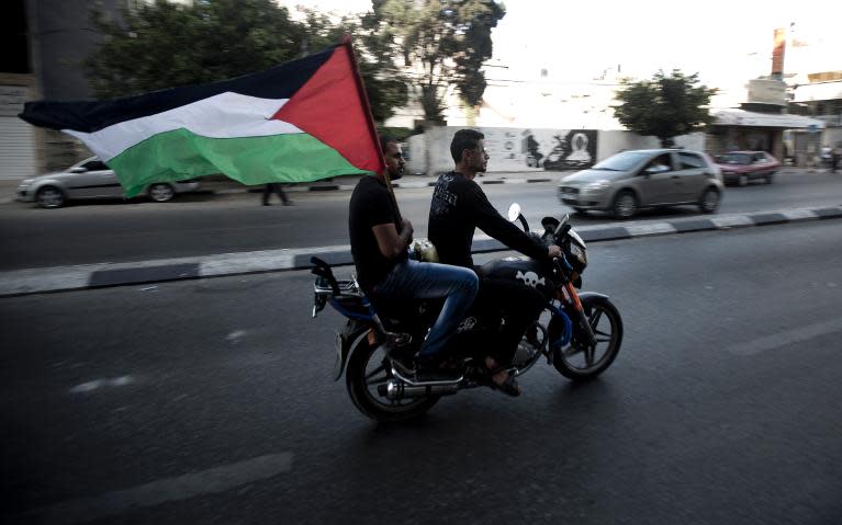 Palestinians carry the national flag as they ride through the streets of Gaza to celebrate the agreement to form a unity government, on April 23, 2014