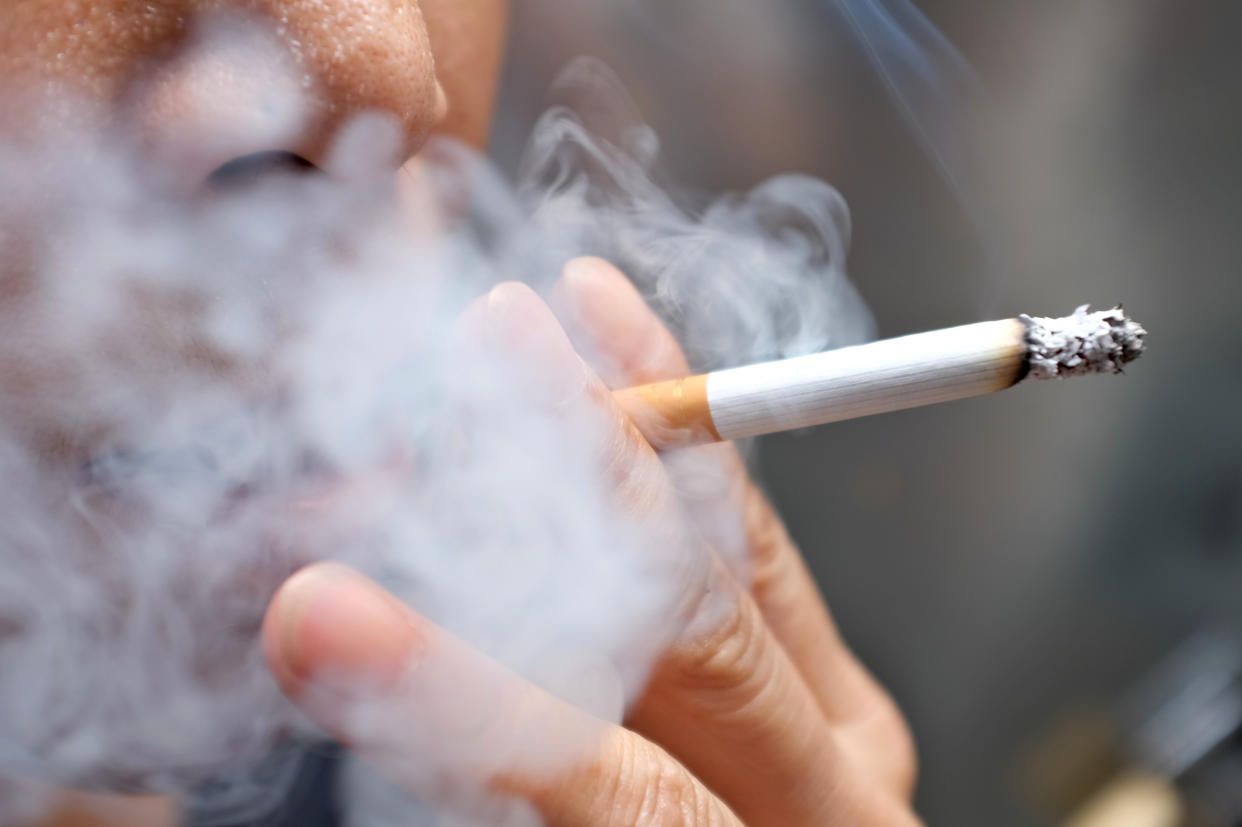 Smoking a cigarette with smoke around and a blurred background