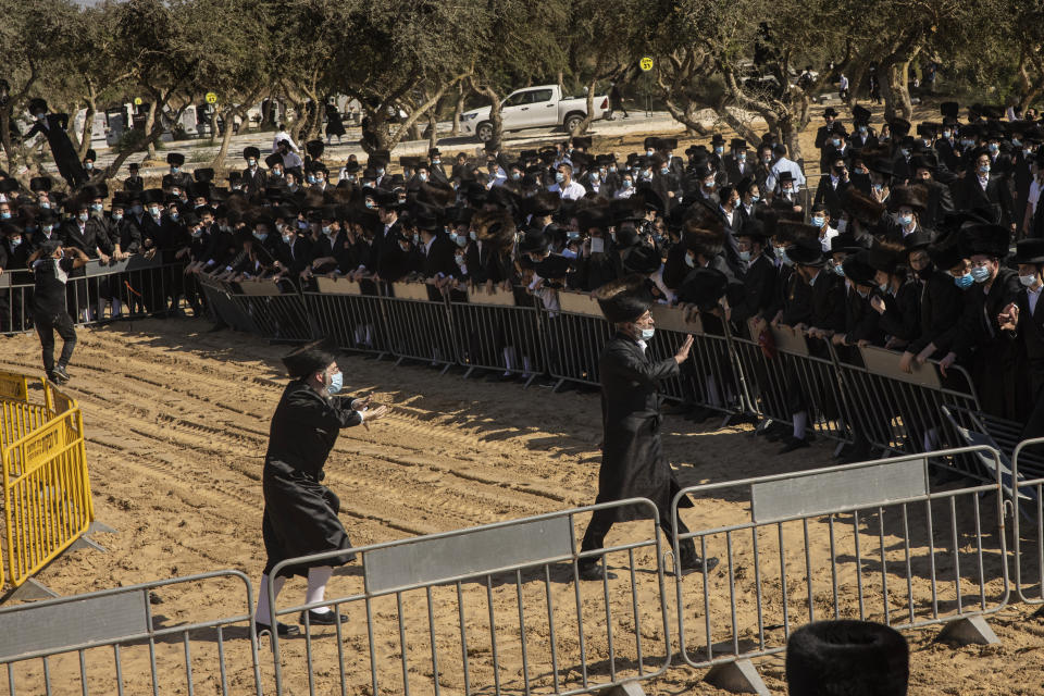 Ultra-Orthodox Jews try to enforce social distancing of mourners gathered for the funeral for Rabbi Mordechai Leifer, in the port city of Ashdod, Israel, Monday, Oct. 5, 2020. The late rabbi, who had been the spiritual leader of a small ultra-Orthodox community founded a century ago in the U.S. city of Pittsburgh, died Sunday after a long bout with COVID-19. (AP Photo/Tsafrir Abayov)