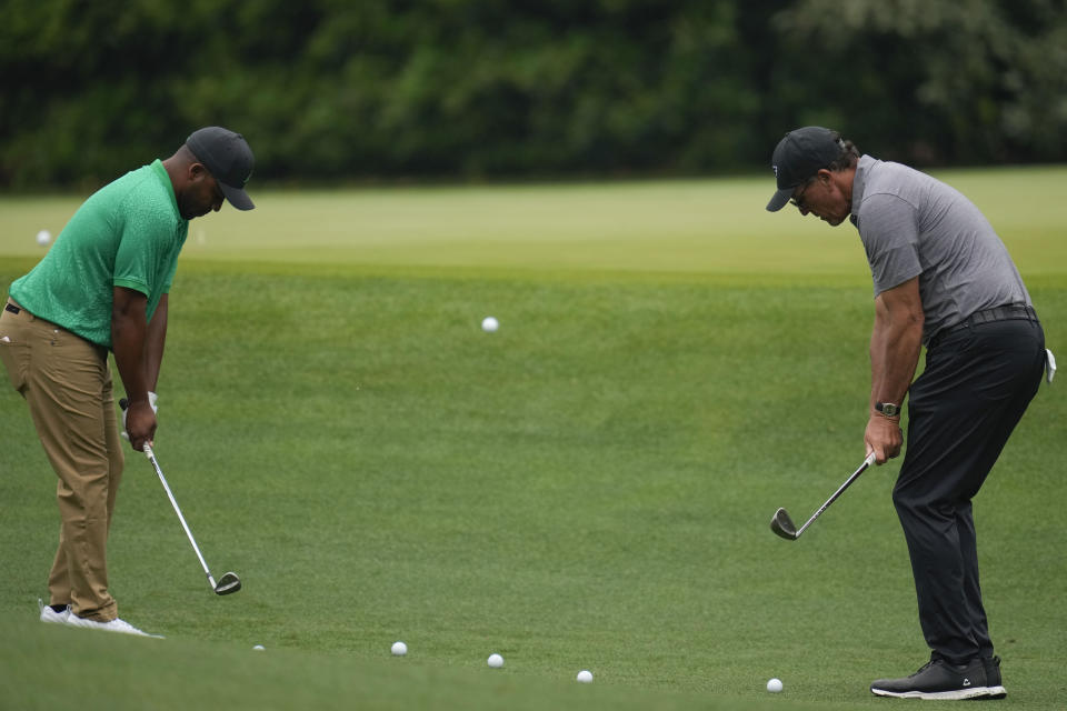 Harold Varner III, left, and Phil Mickelson chip to the 11th green during a practice for the Masters golf tournament at Augusta National Golf Club, Tuesday, April 4, 2023, in Augusta, Ga. (AP Photo/Mark Baker)