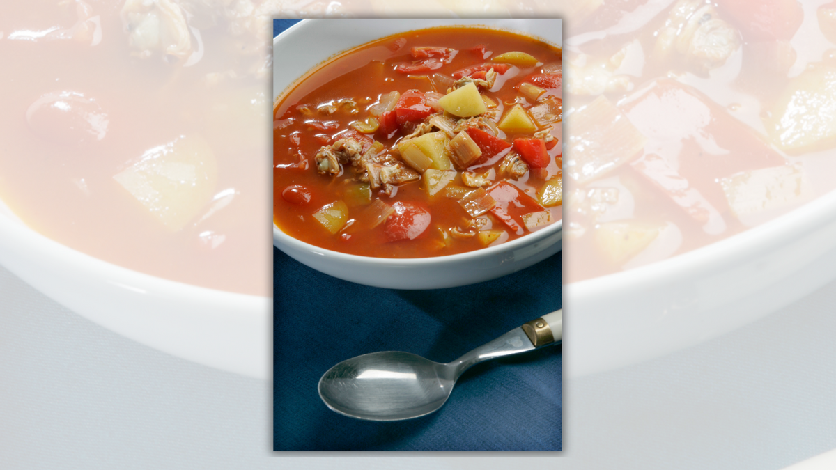 A bowl of soup with a tomato base is next to a soup. 