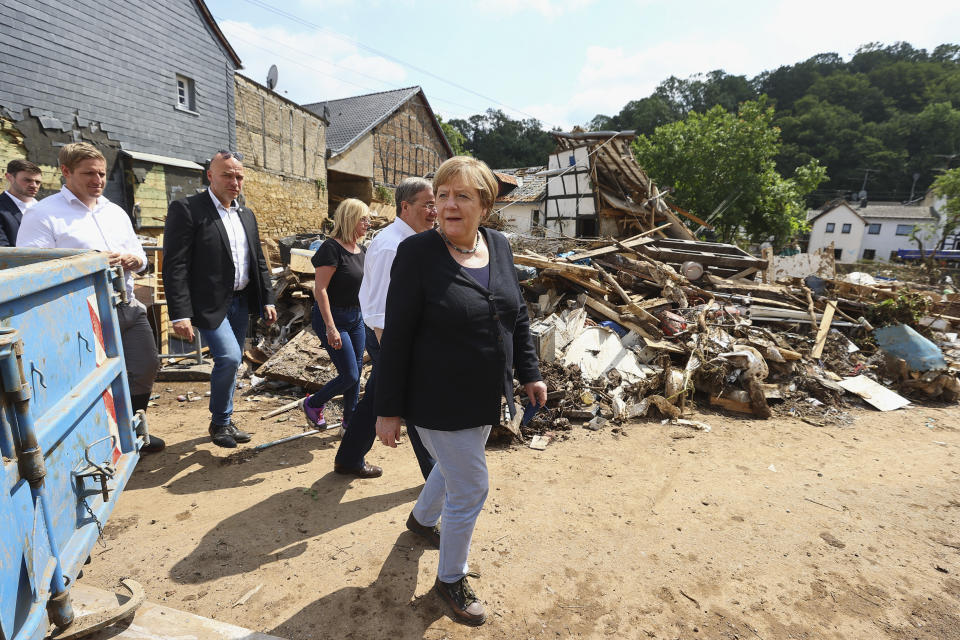 German Chancellor Angela Merkel, center, informs herself in the district of Iversheim about the situation in the flood-affected area and meet victims of the flood disaster Tuesday, July 20, 2021. (Wolfgang Rattay/Pool Photo via AP)