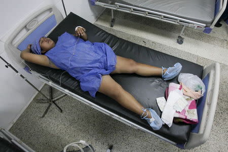 A pregnant woman lays on a bed without sheets during labor at a maternity hospital in Maracaibo, Venezuela June 19, 2015. REUTERS/Isaac Urrutia