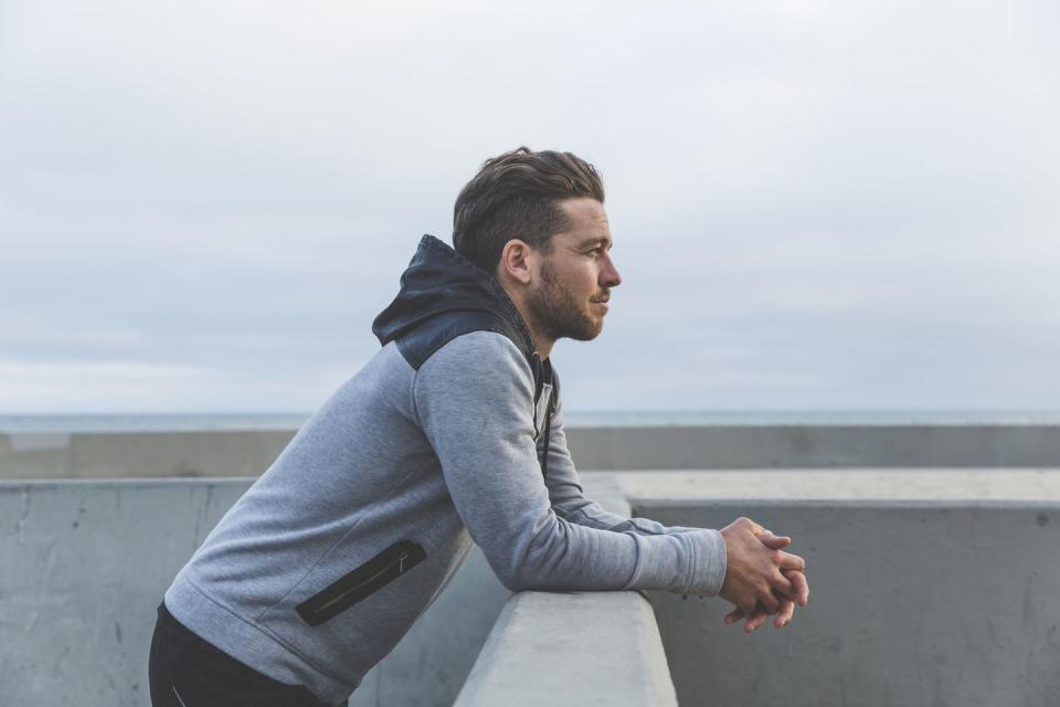 man leaning on wall looking out to sea