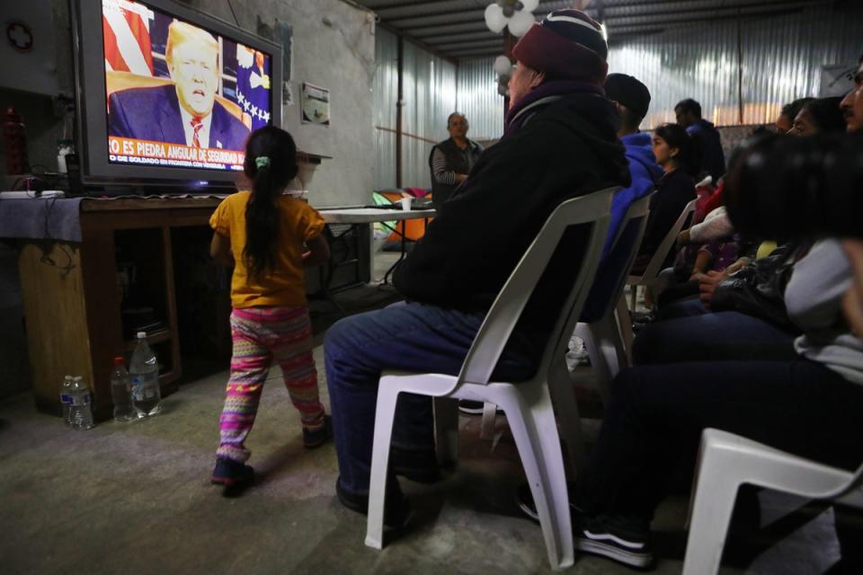 Migrants view a live televised speech by President Donald Trump on border security at a shelter for migrants on January 8, 2019 in Tijuana, Mexico (Getty Images)