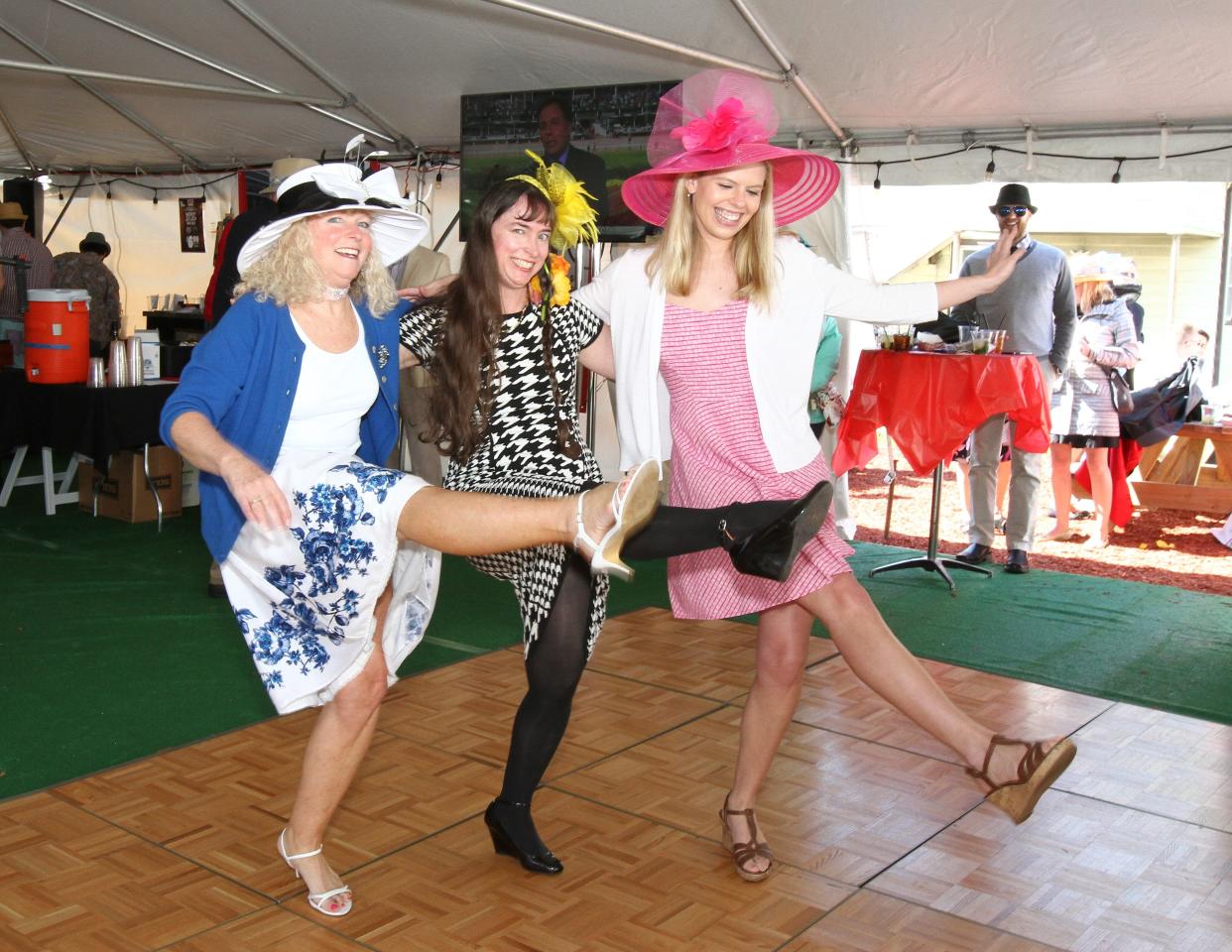 From left, Jenny Nelson, Nancy Shue, and Ann Wallace kick up their heels to the Beer Barrel Polka at a Maxie's Derby Day party.