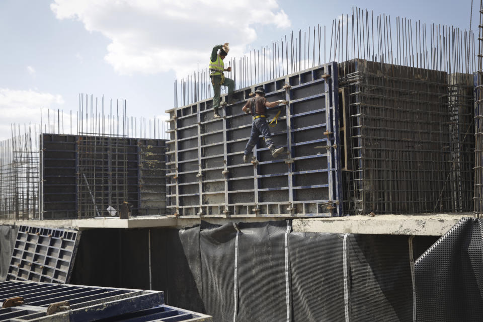 FILE - Workers build an apartment building for residents of Mariupol affected by hostilities, in Mariupol, in territory under the government of the Donetsk People's Republic, eastern Ukraine, on July 1, 2022. According to Russian state TV, the future of the Ukrainian regions occupied by Moscow's forces is all but decided: Referendums on becoming part of Russia will soon take place there, and the joyful residents who were abandoned by Kyiv will be able to prosper in peace. In reality, the Kremlin appears to be in no rush to seal the deal on Ukraine's southern regions of Kherson and Zaporizhzhia and the eastern provinces of Donetsk and Luhansk. (AP Photo)