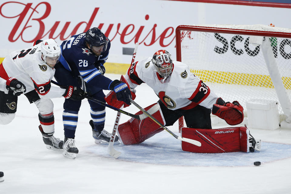 Ottawa Senators goaltender Filip Gustafsson (32) saves a shot by Winnipeg Jets' Blake Wheeler (26) as Senators' Artem Zub (2) defends during second-period NHL hockey game action in Winnipeg, Manitoba, Saturday, May 8, 2021. (John Woods/The Canadian Press via AP)