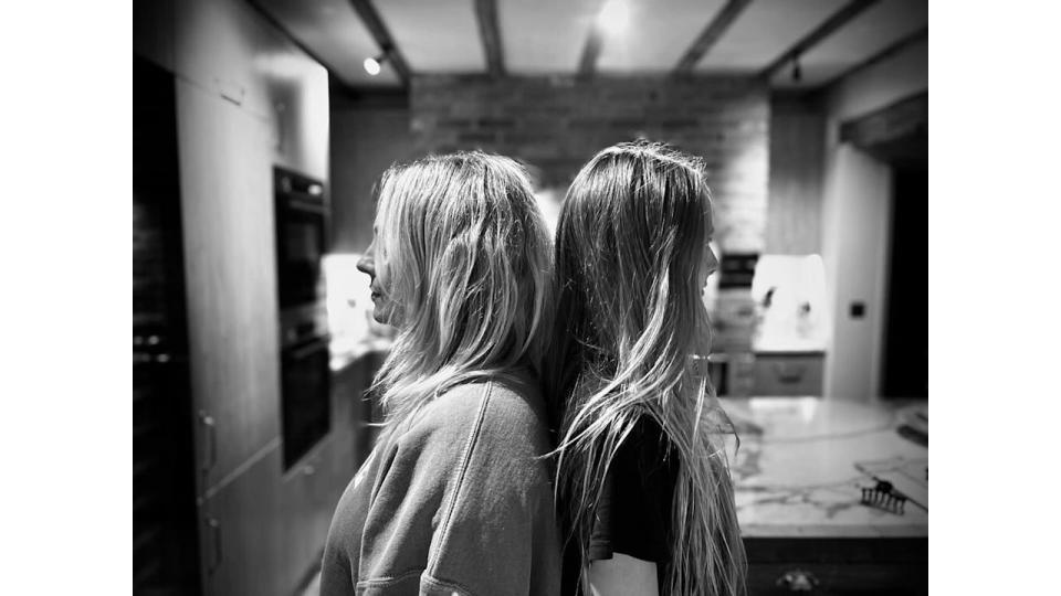 mother and daughter posing back-to-back in kitchen 