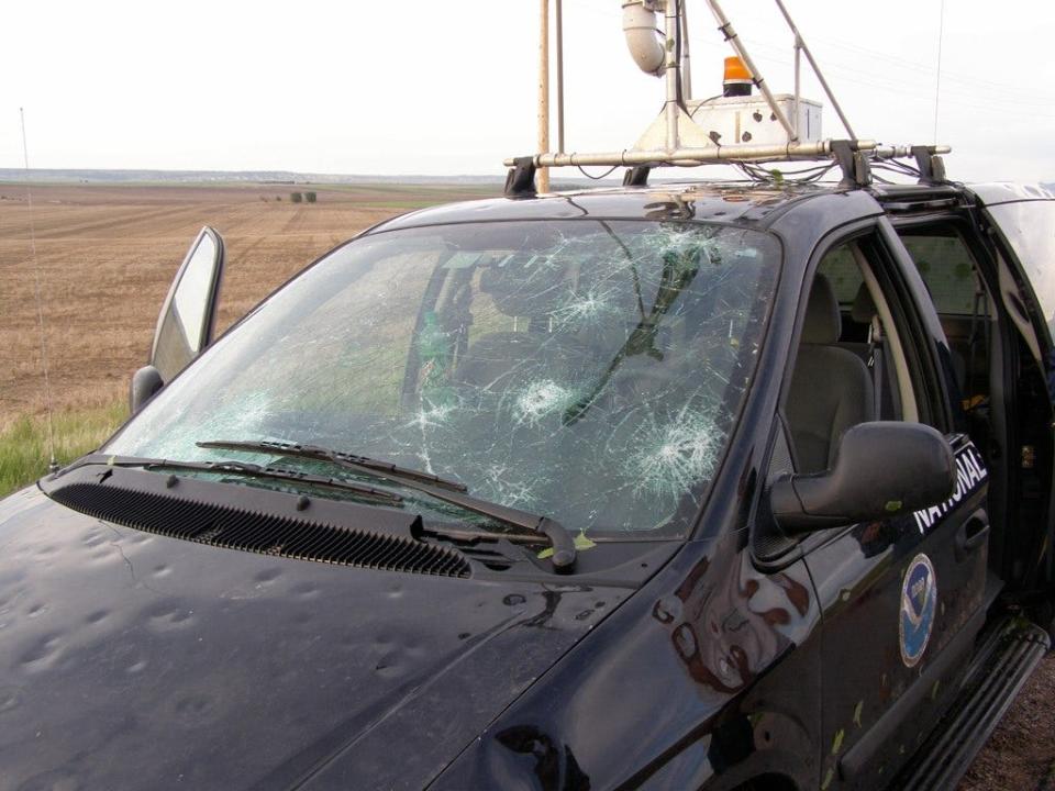 A black SUV with weather monitoring equipment on top and several cracks in the windshield