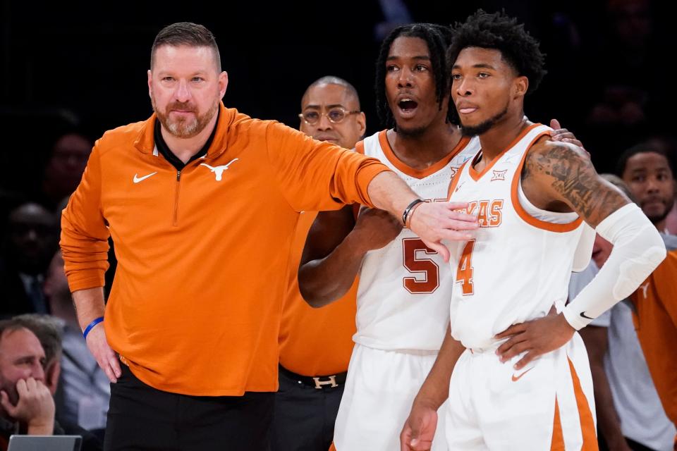 Texas' head coach Chris Beard, left, meets with Tyrese Hunter (4) and Marcus Carr (5) at the bench during the first half of the team's NCAA college basketball game against Illinois in the Jimmy V Classic, Tuesday, Dec. 6, 2022, in New York. (AP Photo/John Minchillo)