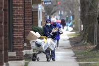 A U.S. postal worker delivers packages, boxes and letters Tuesday, Dec. 22, 2020, along her route in the Hyde Park neighborhood of Chicago, just three days before Christmas. (AP Photo/Charles Rex Arbogast)