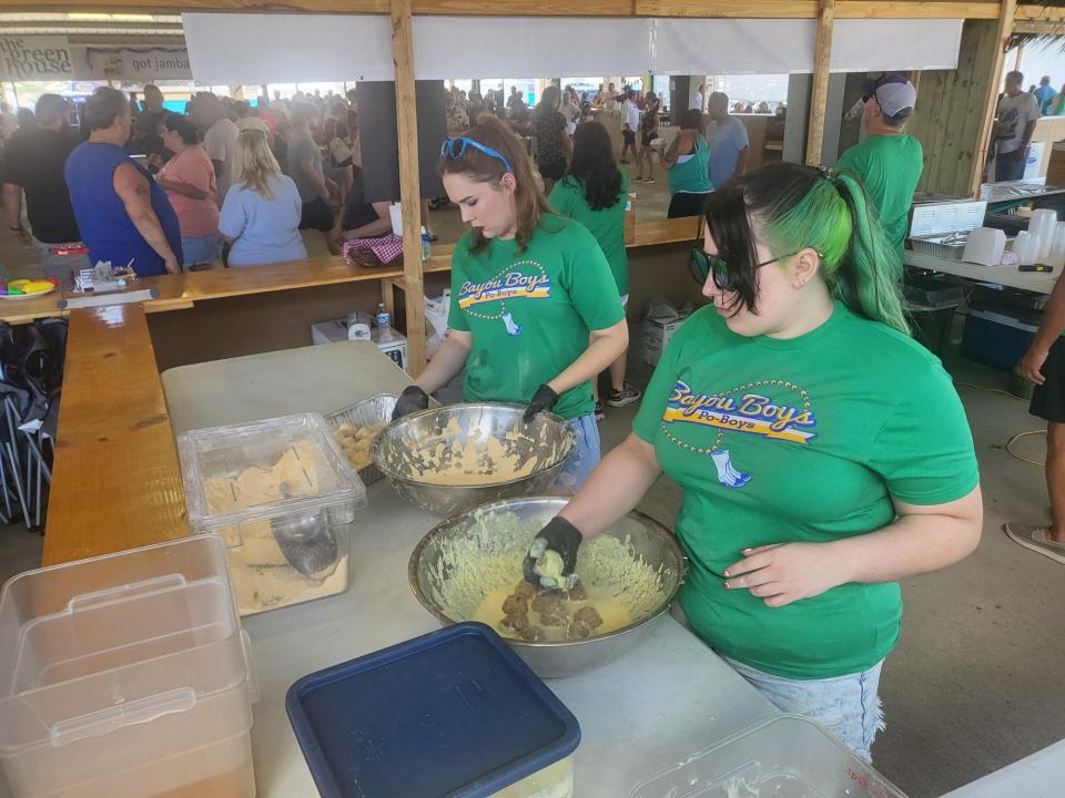 Kristyn Douglas, green hair, and Hanna Redenius, both of Texas, rolling boudin balls at the French Food Festival at the Larose Community Center, Sunday, October 29.