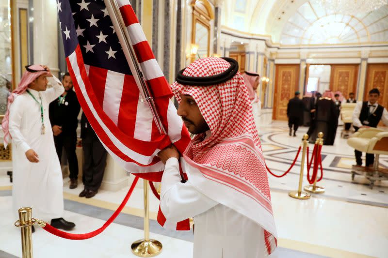 FILE PHOTO: A worker carries a U.S. flag into a meeting room ahead of U.S. President Donald Trump's meeting with Gulf Cooperation Council leaders in Riyadh