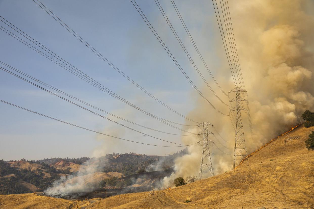 A back fire set by fire fighters burns a hillside behind PG&E; power lines during firefighting operations to battle the Kincade Fire in Healdsburg, Calif. on Oct. 26, 2019.