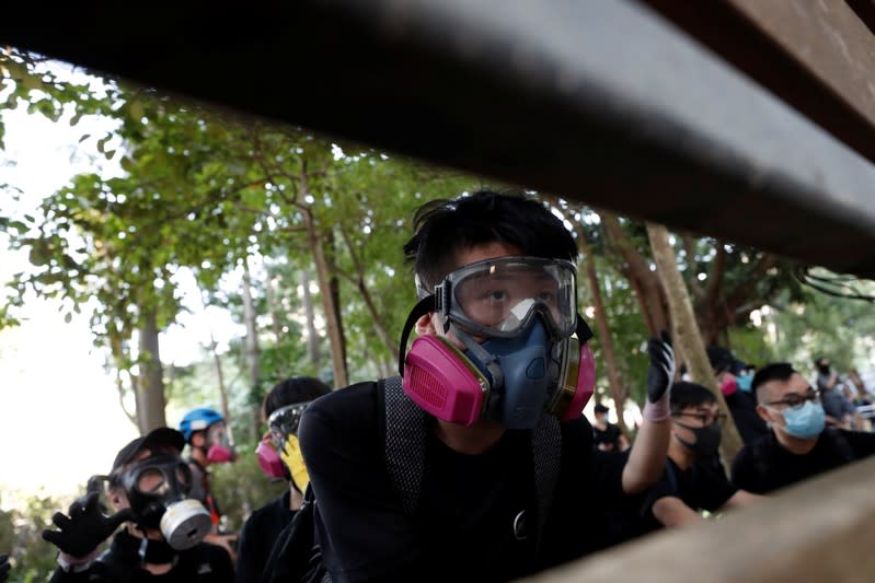 People wearing gas masks stand behind a fence during a protest billed as a global "emergency call" for autonomy, in Hong Kong