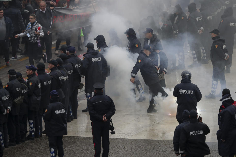 A police officer kicks away a flare thrown by protesters during an anti-government protest in the capital Tirana, Saturday, April 13, 2019. Albanian opposition parties have returned to the streets for the first time since mid-February calling for the government's resignation and an early election, as the center-right opposition accuses the leftist Socialist Party government of Prime Minister Edi Rama of corruption and links to organized crime, which the government denies. (AP Photo/Hektor Pustina)
