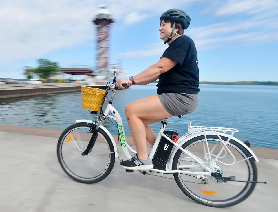 Lynne Mowris, co-founder and chief operating officer of eBIKE DROP, rides an electric bike near the Bicentennial Tower and Presque Isle Bay in Erie in 2022. Her company offers short-term rentals and delivery of e-bikes, which are growing in popularity.