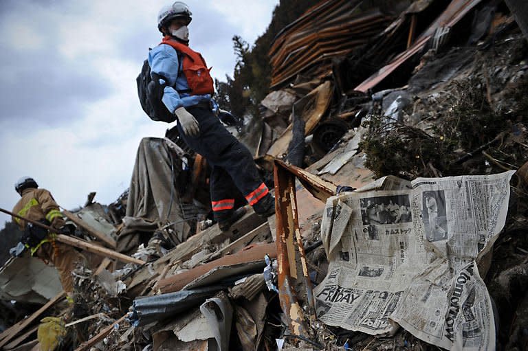 A Japanese fireman amid debris during a search for bodies in Minamisanriku, Myagi province, 10 days after a massive earthquake and tsunami ravaged northeastern Japan. Smoke belched from a stricken nuclear plant in Japan on Monday, disrupting urgent efforts to repair the cooling systems as Tokyo halted some food shipments owing to radiation worries