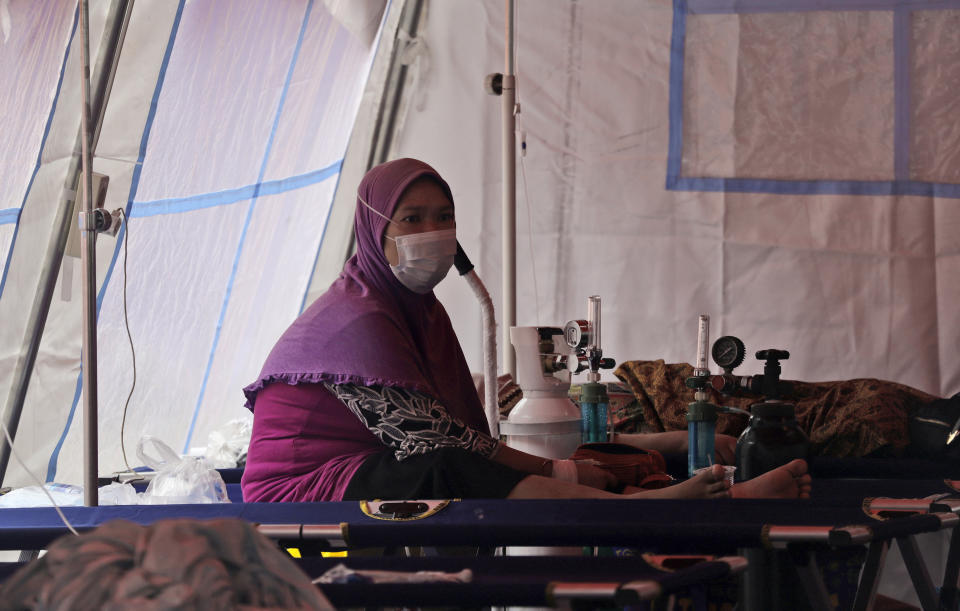 A woman sits inside an emergency tent erected to accommodate a surge of COVID-19 patients at a hospital in Bekasi, on the outskirts of Jakarta, Indonesia, Monday, June 28, 2021. After a slow vaccination rollout, Indonesia is now racing to inoculate as many people as possible as it battles an explosion of cases that have overburdened its health care system. (AP Photo/Achmad Ibrahim)