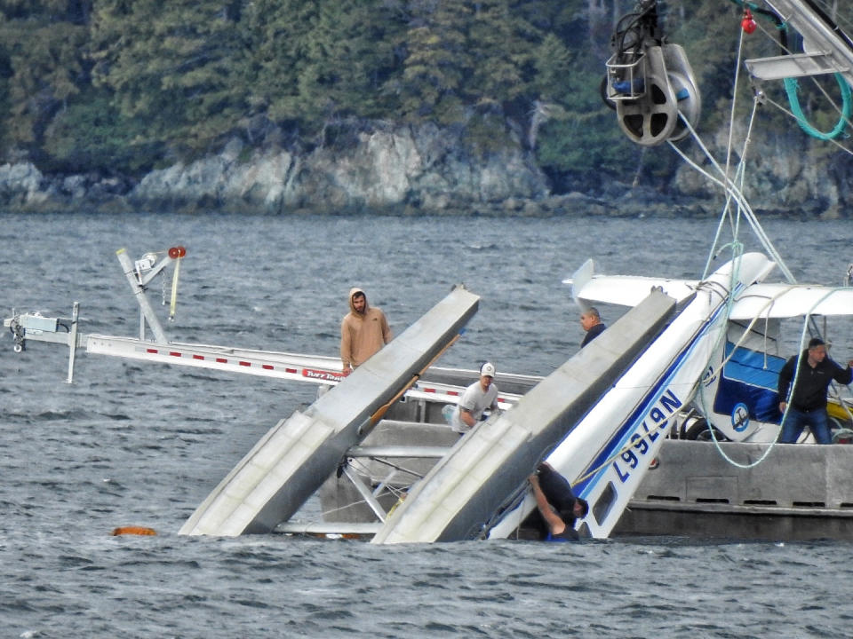 This Monday, May 20, 2019 photo provided by Aerial Leask shows good Samaritans off of fishing vessels attempting to bring in a floatplane that crashed in the harbor of Metlakatla, Alaska. Officials said the pilot and passenger aboard the plane died, and the National Transportation Safety Board is investigating the crash. (Aerial Leask via AP)