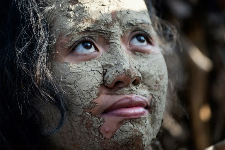 A devotee, with her face covered with mud and wearing a costume made of banana leaves, attends mass during a celebration honouring John the Baptist