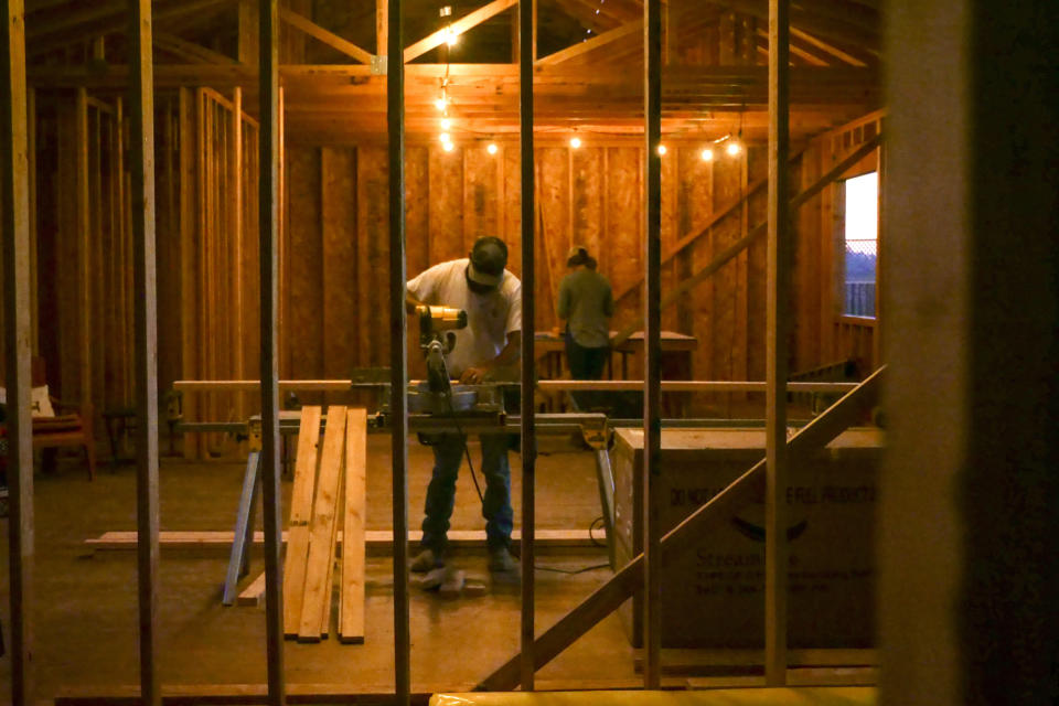 In this Monday, Nov. 4, 2019, photo, Bobbie Chandler, and his wife, Jenna, work in the home they are building in Santa Rosa, Calif., Monday, Nov. 4, 2019. Bobbie's parents' home of 20 years and thousands of other structures were destroyed by the Tubbs Fire and other wine country wildfires of 2017. Bobbie and Jenna bought a lot on their parents' block where a home was destroyed by fire. His brother, Dale, and wife Katrina also bought a lot on the street and plan to build a home there. (AP Photo/Lacy Atkins)