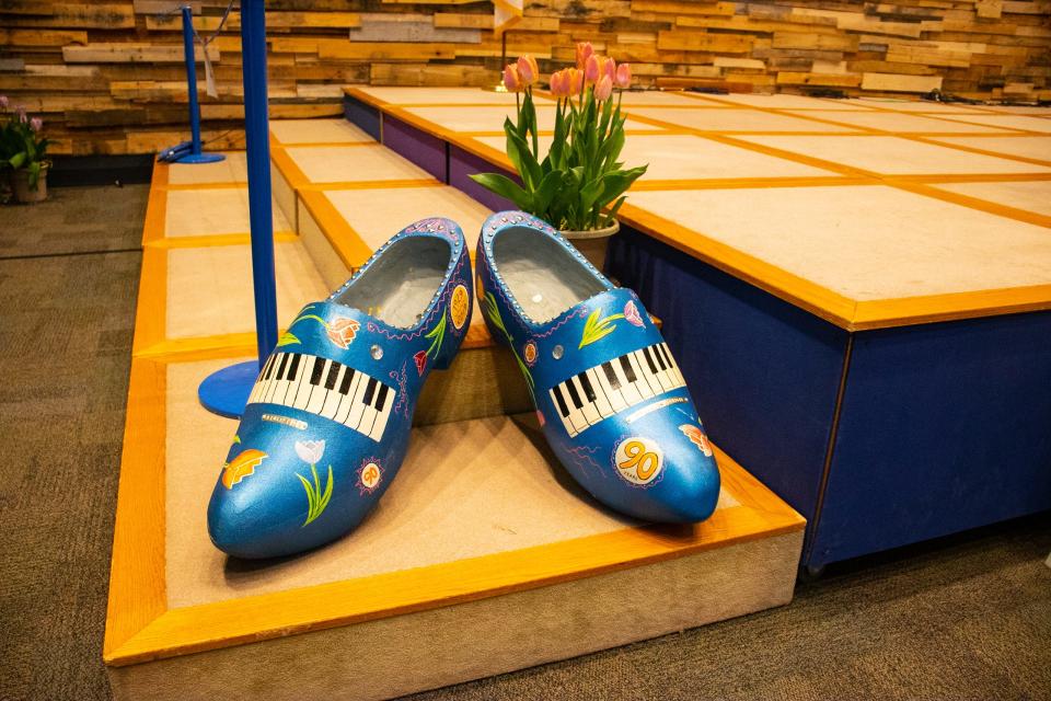 A pair of large, blue clogs with a painting of a piano on them