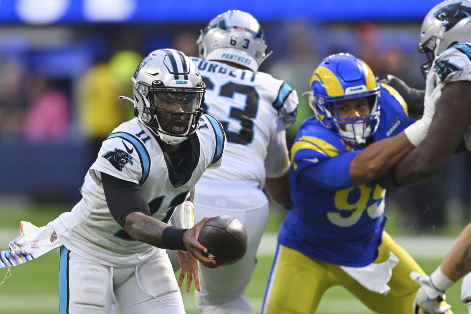 Carolina Panthers quarterback PJ Walker, left, hands off as Los Angeles Rams defensive tackle Aaron Donald (99) closes in during the second half of an NFL football game Sunday, Oct. 16, 2022, in Inglewood, Calif. (AP Photo/Jayne Kamin-Oncea)