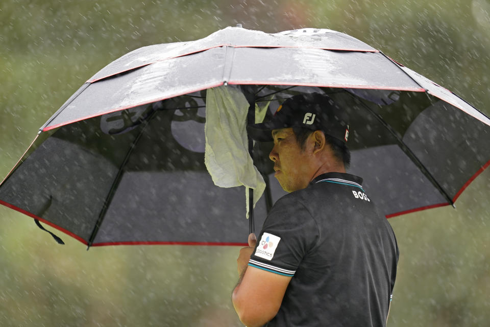 Byeong Hun An, of South Korea, takes cover from rain while waiting to putt on the sixth green of the Silverado Resort North Course during the final round of the Fortinet Championship PGA golf tournament in Napa, Calif., Sunday, Sept. 18, 2022. (AP Photo/Eric Risberg)