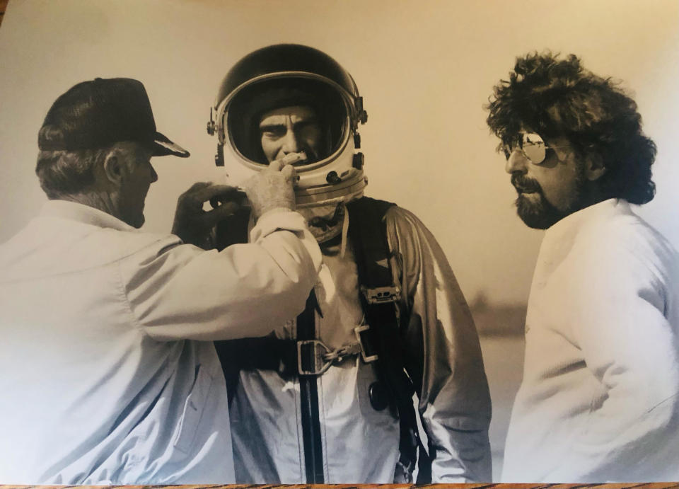 two men stand beside an actor in a spacesuit