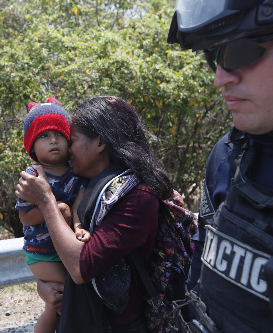 Una mujer migrante centroamericana y su hijo caminan con un agente de la Policía Federal de México mientras son detenidos en la carretera a Pijijiapan, México, el lunes 22 de abril de 2019. La policía mexicana y los agentes de inmigración detuvieron a cientos de migrantes centroamericanos el lunes en la mayor redada en una caravana de migrantes desde que los grupos comenzaron a moverse a través de México el año pasado. (AP Foto/Moisés Castillo)