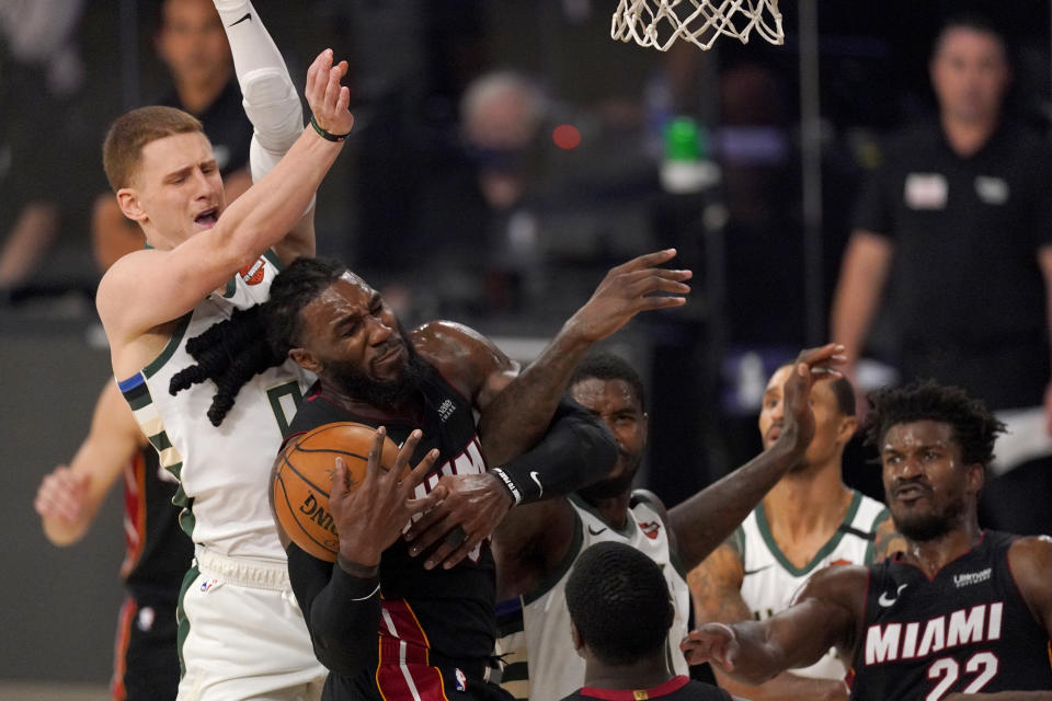 Milwaukee Bucks' Donte DiVincenzo, left, defends as Miami Heat's Jae Crowder (99) competes for control of a rebound during the second half of an NBA basketball conference semifinal playoff game, Monday, Aug. 31, 2020, in Lake Buena Vista, Fla. The Heat's Jimmy Butler (22) looks on during the play. (AP Photo/Mark J. Terrill)