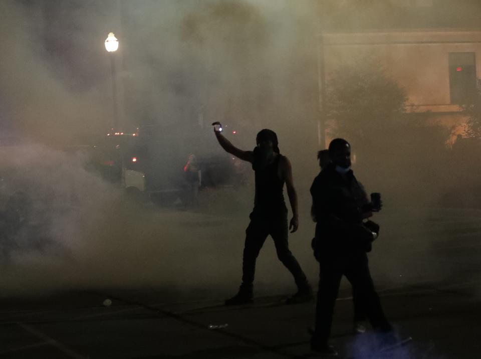 A man records cellphone video as tear gas is used on protesters outside the Kenosha Police Department on Sunday, Aug. 23, 2020.