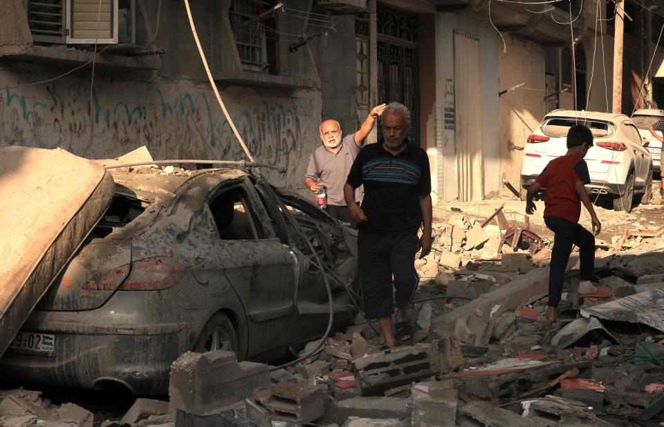 Palestinians walk amid the rubble and destruction after an Israeli airstrike on Gaza (AFP via Getty Images)