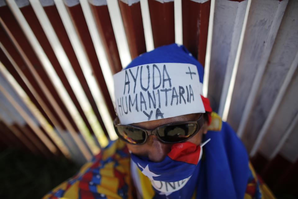 FILE - In this Feb. 23, 2019 file photo, an opposition supporter wears a message on his forehead that reads in Spanish: "Humanitarian aid now" during a demonstration urging soldiers to allow the entry of U.S. humanitarian aid, in Caracas, Venezuela. As Venezuela's opposition rekindles street protests and builds powerful international support, the millions who fled are redirecting their gaze toward their beloved homeland in hopes that their exile will prove short-lived. (AP Photo/Ariana Cubillos, File)