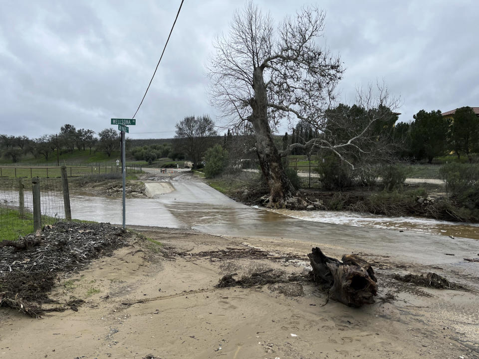 In this photo provided by Neil Collins, rain flows at the intersection of Wellsona Rd. and San Marcos Rd. near the San Marcos Creek on Wednesday, Jan. 11, 2023, in San Miguel, Calif., captured about 15 minutes before a vehicle driven by Lindsy Doan and carrying her son, Kyle Doan, was swept away by rising floodwaters. The mother was eventually rescued, but her 5-year-old son remains missing. (Neil Collins via AP)